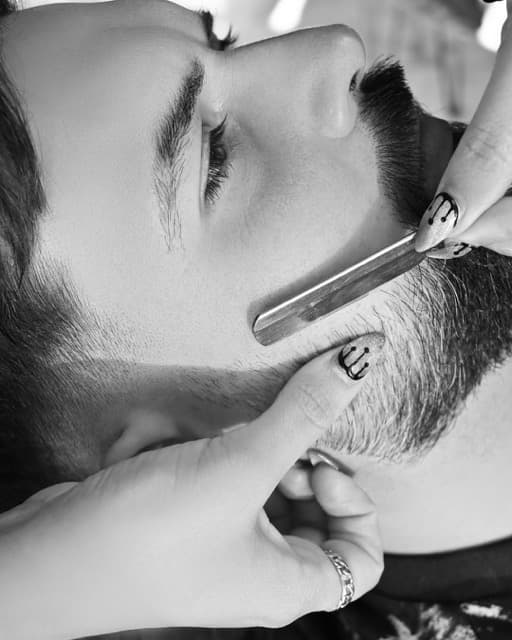 Barber shaping a beard with a straight razor at TJ Barber on the Coast Road