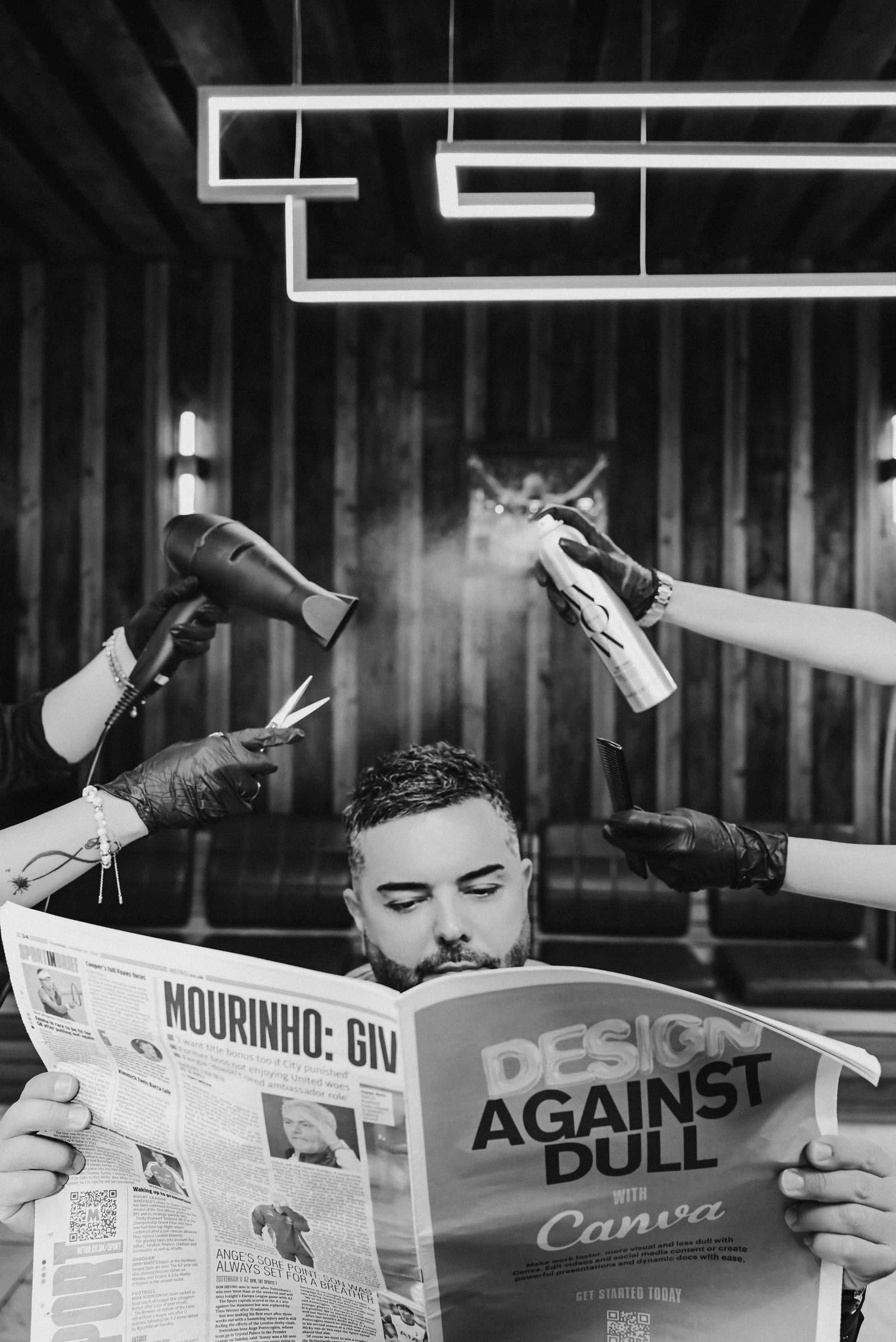 Client reading a newspaper while being styled at TJ Barber